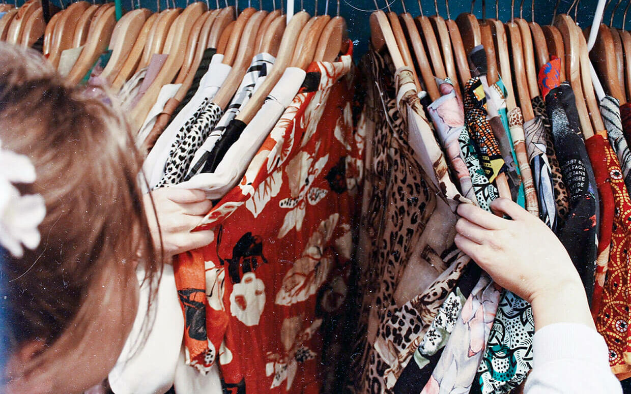 vintage store shopper looking through button down printed shirts