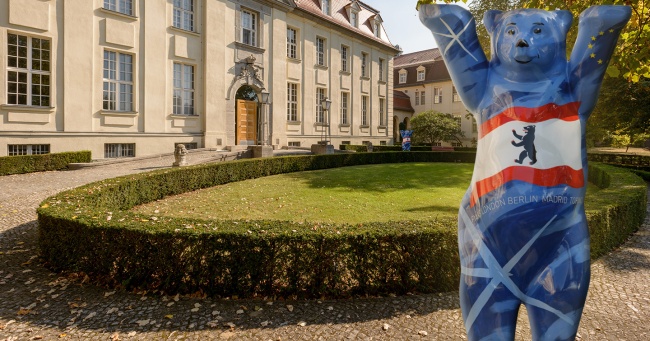 Garden in front of the entrance gate to the Berlin campus with the United Buddy Bear statue in the foreground